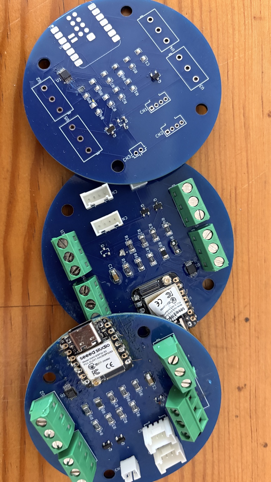 Three round well-bouy01 boards at different assembly stages — casualties of hand-soldering the fine-pitch ADS1115